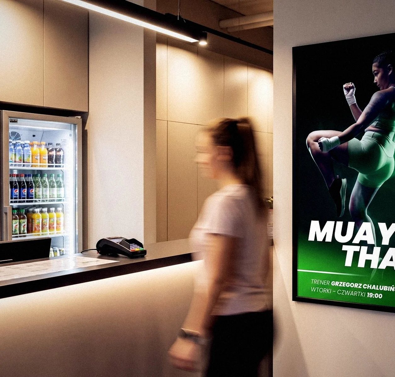 Plakat zajęć w ramie przy recepcji klubu FitFabric